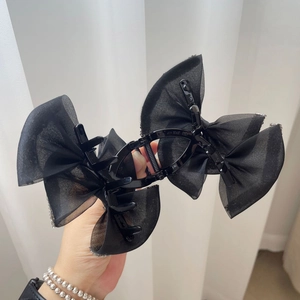 Close-up of black hair claw clip with organza bow and silver sequins details