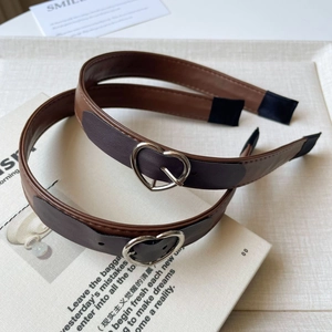 Brown leather headband with silver heart buckle on vintage book background