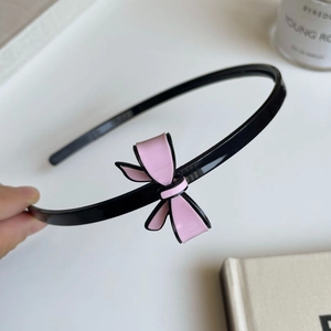 Detailaufnahme des eleganten rosa Haarreifs mit Schleife und schwarzem Rand auf Harz