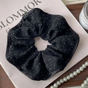 French style black polka dot scrunchie with satin edge on a minimalist aesthetic background