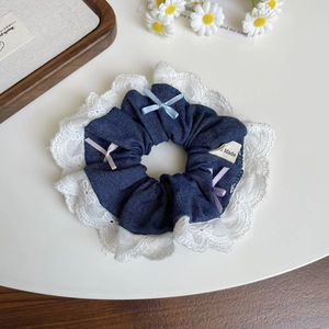 Vue détaillée du chouchou en jean avec des nœuds colorés et des finitions en dentelle