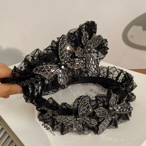 Serre-tête en dentelle avec strass gris et breloques papillon sur un support blanc