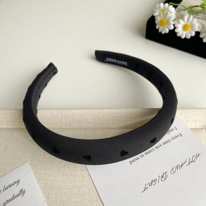 Détail du serre-tête noir fait main avec motifs de cœurs et étiquette tissée