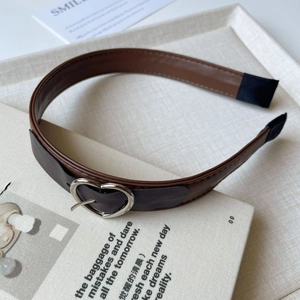 Close-up of vintage dark brown leather headband with a silver heart-shaped metal buckle detail