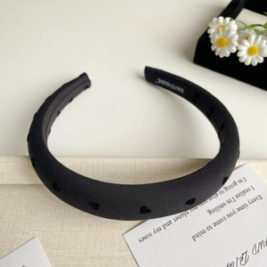 Détail d'un serre-tête noir rembourré avec motifs de cœurs et étiquette Hand Made artisanale