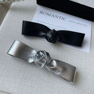 Détail de pinces à cheveux en cuir noir et argent avec motif de fleur de rose centrale
