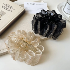 Detailed close-up of large floral chiffon hair claws with rhinestones on a stylish tray