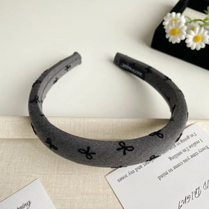 Détail du bandeau en tissu gris avec broderie de nœuds noirs et étiquette faite à la main