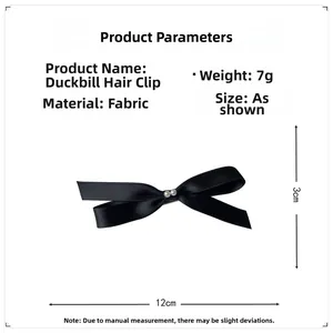 Detail showing a black satin bow hair clip with faux pearls and metal alligator clip