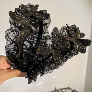 Détail de paillettes et papillons en strass sur un bandeau large en dentelle noire