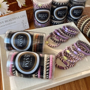 Close-up of elastic woven hair ties with decorative beads in a cylindrical container