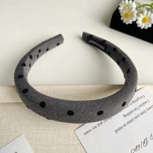 Détail d'un serre-tête gris rembourré à pois avec étiquette faite main en tissu lin