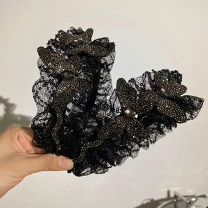 Détail du bandeau en dentelle noire avec des paillettes et des ornements de papillons