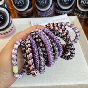 Detail of high-elasticity braided hair ties set in various colors with storage jar