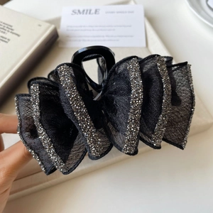 Close-up of elegant black ribbon hair claw clip with sparkling silver rhinestones