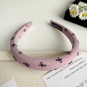 Détail d'un serre-tête en tissu rose à motifs nœuds et étiquette artisanale intérieure