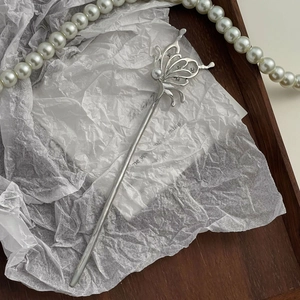 Elegant silver butterfly hair pin with pearls and rhinestones on a wooden tray