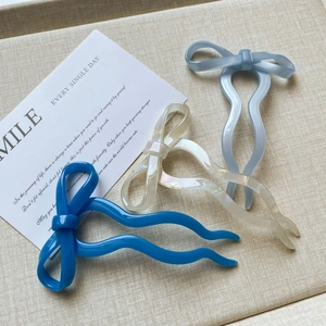 Detail view of ballet-style bow hairpins in glossy blue, pearly white, and grey finishes