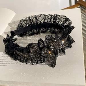 Détail d'un serre-tête en dentelle noire orné de paillettes et de papillons en perles