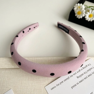 Détail d'un serre-tête rose à pois en velours avec une étiquette de fabrication artisanale