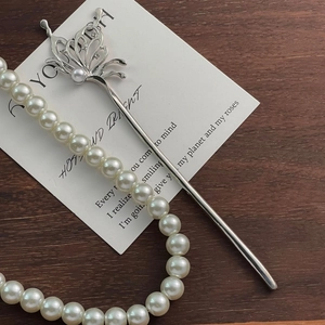 Macro view of silver butterfly hair pin with pearls and rhinestones on wood