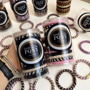 Close-up of woven elastic hair ties in various colors packed in a clear round bottle