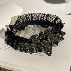 Détail d'un serre-tête en dentelle noire avec paillettes et papillons ornés de cristaux