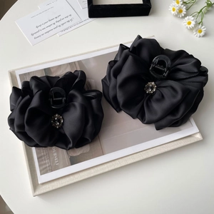 Elegant black satin bow hair claw clip with rhinestones and pearls on a white surface