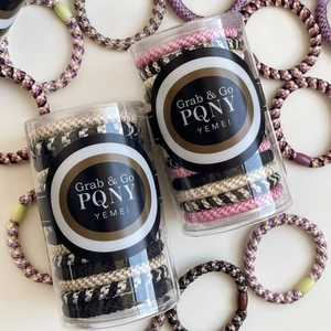Elastic braided hair tie set in cylinders featuring multiple colors and durable fabric