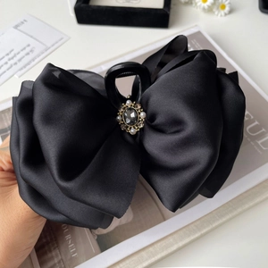 Detail of elegant black satin bow hair claw clip with crystal and pearl centerpiece