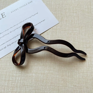 Detailed view of dark tortoiseshell acetate bow hairpin with wave design for hair styling