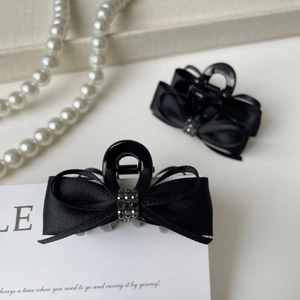 Detail of elegant black satin ribbon bow hair clips with sparkling rhinestone accents