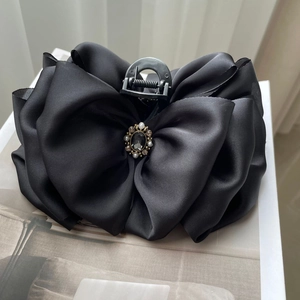 Detail of elegant black satin bow hair claw with vintage pearl and rhinestone center