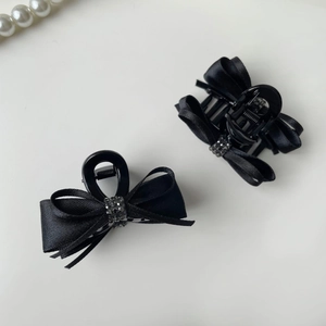 Detailed close-up of a black ribbon bow hair clip featuring sparkling black rhinestones