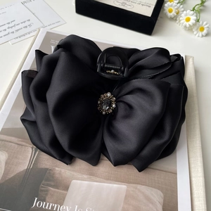 Detail of elegant black satin bow hair claw with crystal centerpiece and faux pearls