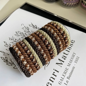 Macro shot of elastic spiral hair ties in earth tones on a transparent cylinder display