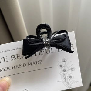 Macro shot of elegant black satin bow hair claw clip with charcoal grey rhinestone detail