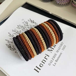 Close-up of high-elasticity braided hair ties in earthy tones displayed on a clear rack