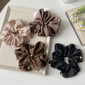 Silk satin scrunchie set in earth tones with white pearl accents on a neutral tray