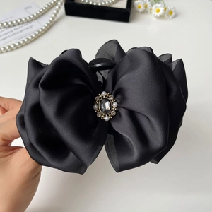 Detail of elegant black satin bow hair claw with pearls and rhinestones decoration