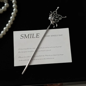 Detail of silver metal hair stick featuring a hollow butterfly design with pearls
