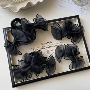 Détail de quatre pinces à cheveux noeud en organza noir sur un plateau vintage