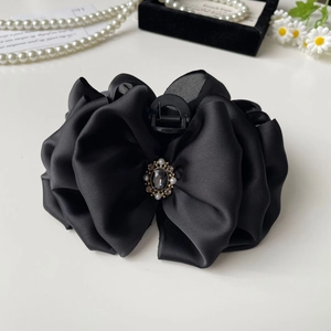 Detailed view of large black satin bow hair claw with pearl and rhinestone inlay