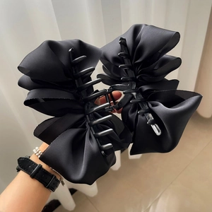 Detailed close-up of the multi-layered black satin fabric texture on this large bow hair claw