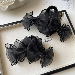 Gros plan de pinces à cheveux à nœud en organza noir sur un plateau décoratif chic