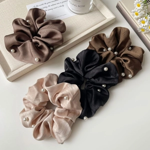 Detail of four silk satin scrunchies with white pearls in coffee and champagne tones