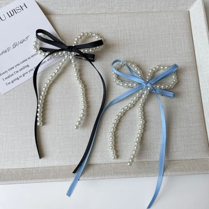 Detalle de pinzas para el pelo con lazo y borlas largas de perlas en negro y azul cielo