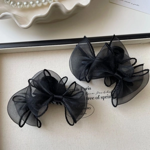 Détail de pinces à cheveux à nœud en organza noir sur un présentoir de bijoux chic