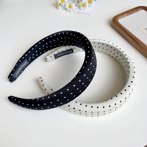 Detailed view of polka dot sponge headbands with handmade label on white desk