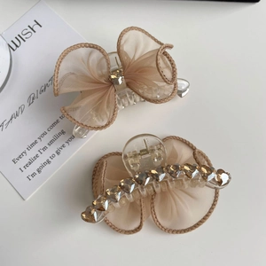 Détail de barrettes nœuds en maille avec strass et accents de pierres en forme de cœur